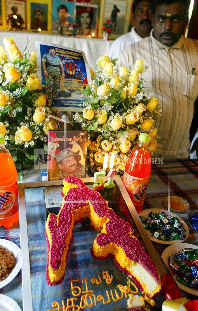 A Tamil Tiger rebel supporter stands next to a photograph of Tamil rebel leader Velupillai Prabhakaran and a cake, made in shape of Eelam, the land claimed by Tamil rebels at Sakkotai, Jaffna 2005.jpg