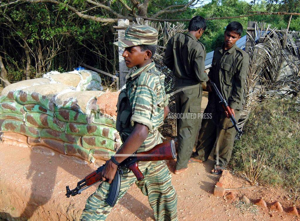 Two Tamil Tiger rebel fighters stand vigil at a road block on a road which links government controlled area and the rebel held Sampur village, close to the eastern city of Trincomalee.jpg