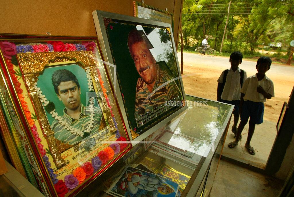 Tamil schoolchildren stand at the doorway of a framing shop that displays the picture of a Tamil Tiger killed in action, along with the picture of the Tamil Tiger leader Vellupillai Prabhakaran, right, in kili.jpg