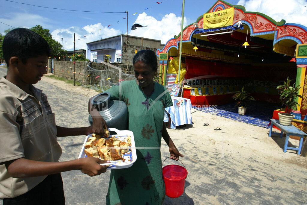 A Tamil Tiger supporter offers cake to a woman during celebrations of the 51st birthday of Tamil rebel leader Velupillai Prabhakaran at Sakkotai, in northern Jaffna peninsula 2005 26.jpg