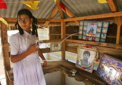 A girl from Sencholai lights a lamp in front of the photographs of Tamil Tiger rebels who died in the war against the Sri Lankan government, in Kilinochchi, jn 22 2006.jpg