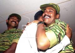 A leader of the Liberation Tigers of Tamileelam (LTTE) Col. Banu, right, hugs Kennedy, a freed prisoner of the LTTE, as Col. Jeyam left, looks on at a location close to Omanthai, sept 28, 2002.jpg