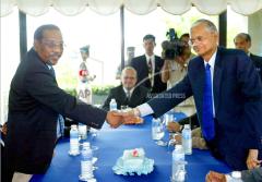 G.L. Peiris, right, shakes hands with the rebel Tamil Tiger delegation's chief negotiator Anton Balasingham as Norway's chief facilitator of the talks Vidar Helgesen, center, looks on at a Thai naval base Monday, Sept. 16, 2002..jpg
