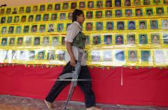 A woman Tamil Tiger rebel fighter walks past a rows of pictures of their fallen fighters in rebel controlled eastern city of Karadiyanaru Nov 25, 2005.jpg