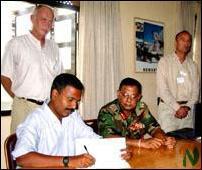 sub-committee_trinco_3_211102 Mr.Tilak signs the minutes of the discussion while Major General Shantha Kottegoda looks on. The Head of the SLMM in Trincomalee Mr.Jan Ledang and Monitor Mr.Abdel Burkan are seen behind them..jpg